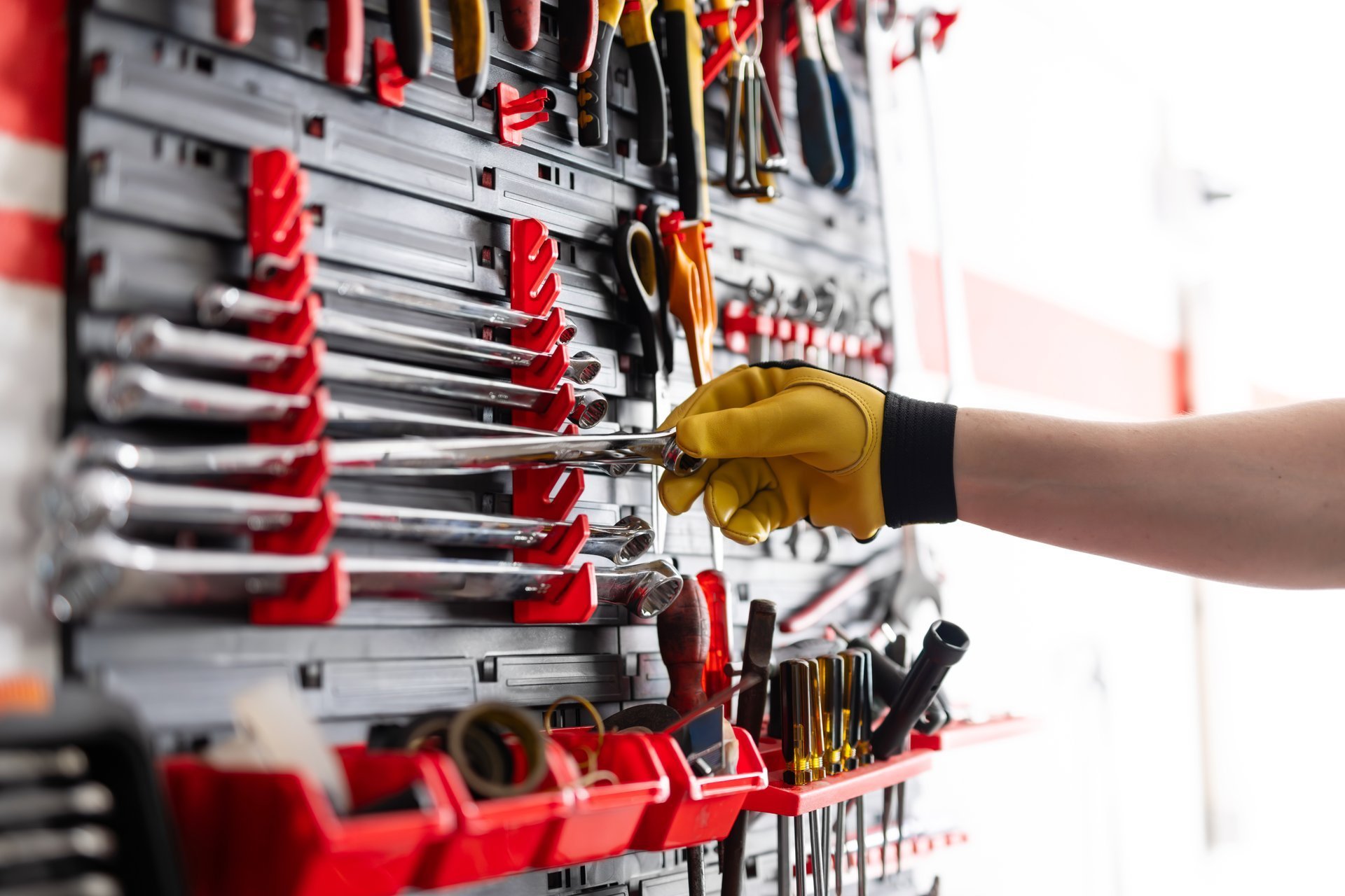 Mechanic Choosing A Wrench From A Garage Wall-Mounted Tool Organizer